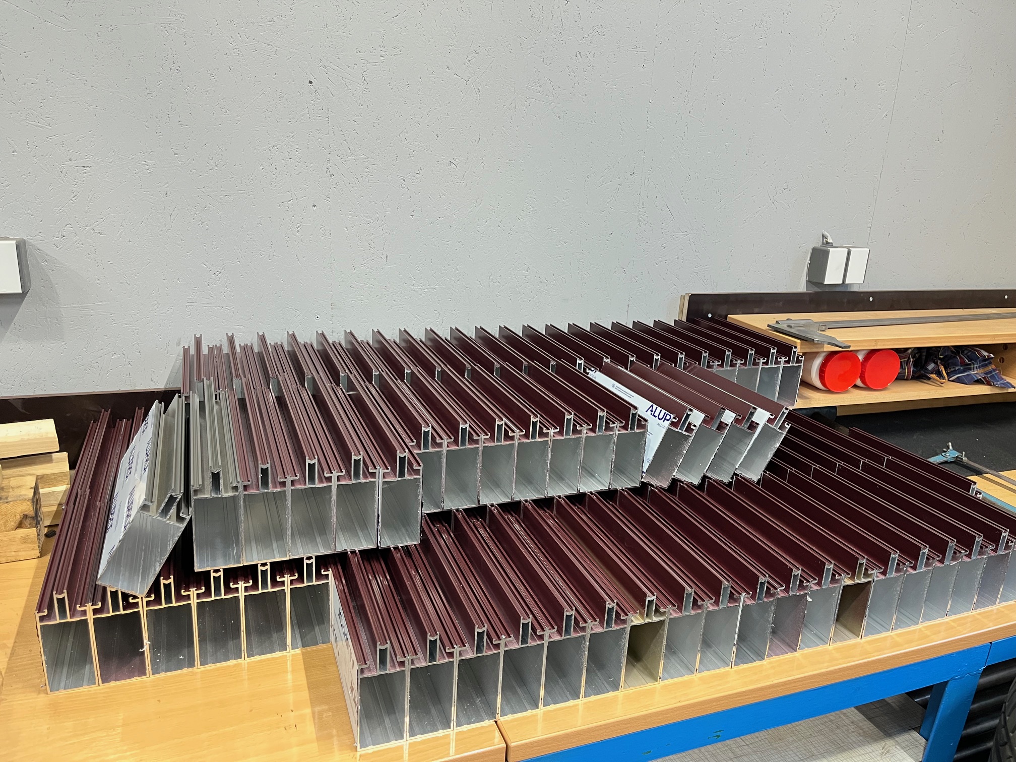 Stoh hliníkových profilů připravených na montáž, uložených na pracovním stole.