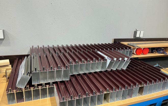 Stoh hliníkových profilů připravených na montáž, uložených na pracovním stole.