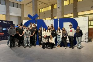 Skupina studentů stojící před velkou modrou instalací s písmeny ČNB uvnitř budovy banky.